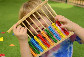 Cute boy is getting ready for school, learning to count on colored abacus. Lessons for preschoolers in kindergarten.
