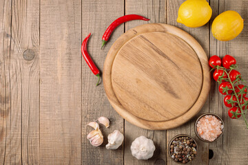 Wooden Cutting Board with Fresh Herbs and Raw Vegetables on Rustic Wood Table. Top view. Cooking...