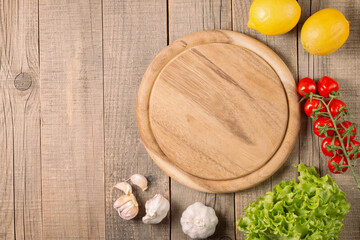 Wooden Cutting Board with Fresh Herbs and Raw Vegetables on Rustic Wood Table. Top view. Cooking background.