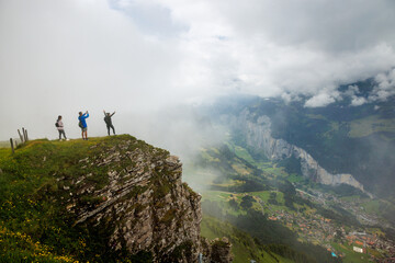 hikers on Männlichen taking pictures through clouds in Lauterbrunnen valley