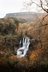Autumn landscape of the Peñaladros waterfall and the Ayala valley with the Gorobel or Sierra Salbada mountain range in the background