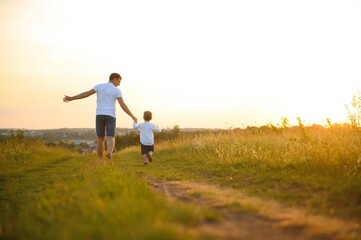 Fototapeta na wymiar father's day. Dad and son playing together outdoors on a summer. Happy family, father, son at sunset.