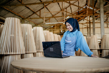 veiled businesswoman working using a laptop pc on table in wood craft store