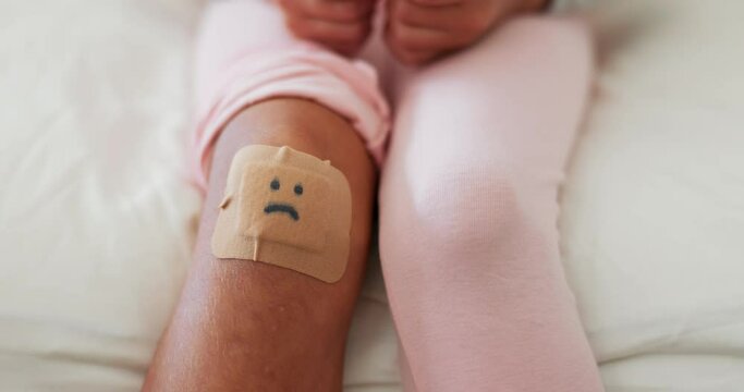 Knee bandage, child and hand for care, first aid support and love after a fall or accident. Sad, house and a kid with a plaster on leg and a parent with help and healthcare after injury together