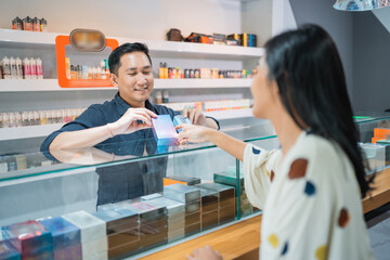 Obraz premium female customer pointing on the one of the vape mods that offered by the male shopkeeper at the vape store