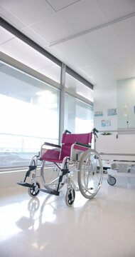 Vertical video of empty wheelchair and patient bed in the hospital ward