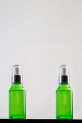 A green glass dropper bottle on white background