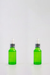 A green glass dropper bottle on white background