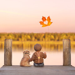 kleiner Junge mit seinem Hund im Herbst am See