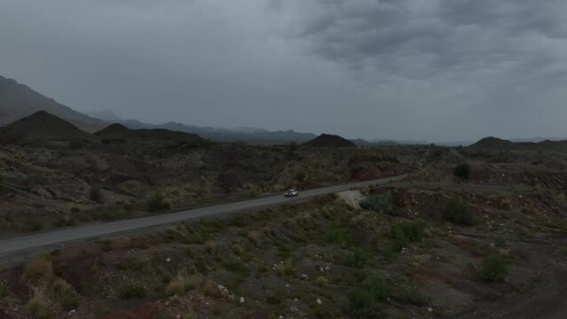 Aerial drone shot tracking a truck driving on a highway in a beautiful mountain landscape in Balochistan