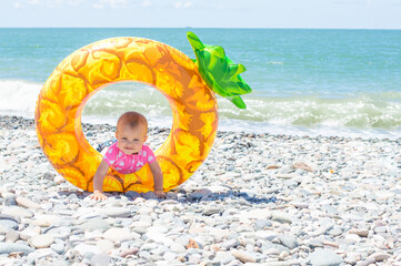 little girl with a giant rubber swim ring at the water's edge on the beach
