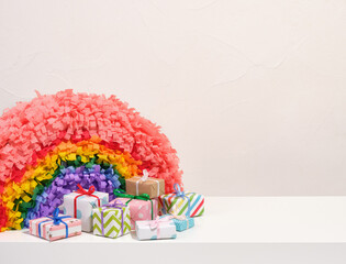 Rainbow pinata and colorful gifts wrapped in beautiful paper with gift bows. Copy space for text.