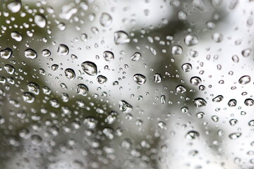 Window glass with condensation, high humidity, large drops of water flow down the glass. Cool color tones on the image