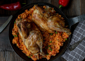 Baked chicken with serbian djuvec rice and vegetables in a frying pan on  wooden background