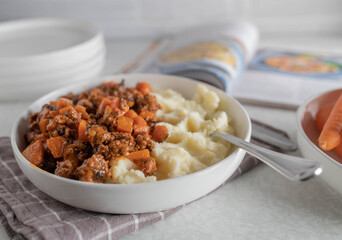 Plate with ground beef, carrots and mashed potatoes on kitchen counter. Home cooked meal