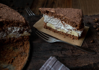 Tiramisu cake with bananas on a wooden background. 