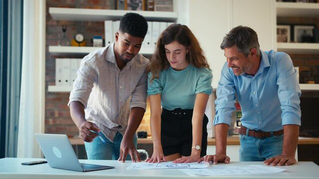 Male and female architects with laptop meeting and discussing building plans in modern office - shot in slow motion