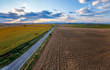 Fototapeta na wymiar aerial view of a rural landscape with a asphalt road, against the sunset