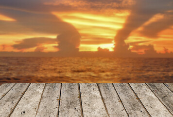 Wooden board empty table on front of blurred background. Blurry sunset on the beach.