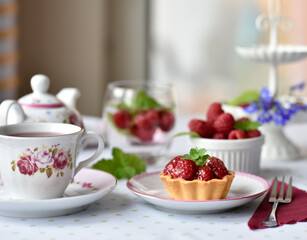 Mini tarts with raspberries served with tea on the table