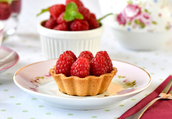 Mini tarts with raspberries served with tea on the table