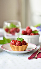 Mini tarts with raspberries served with tea on the table