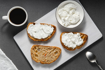 Sandwiches with cottage cheese and bread with carrots on a gray table