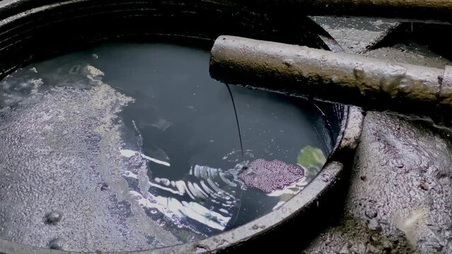 Black chemical wastewater on the storage tank coming out from pipe from industrial processes. Hazardous and toxic waste water - WWTP Wastewater Treatment Procedure