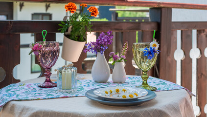 Table on the terrace with soft drinks, flowers and a plate of daisies