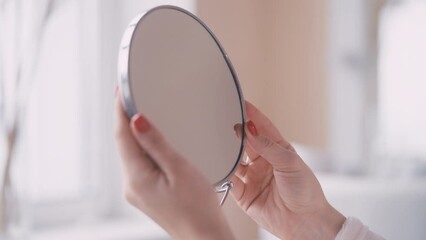 Close-up of female hands holding round mirror, beauty procedures, cosmetology