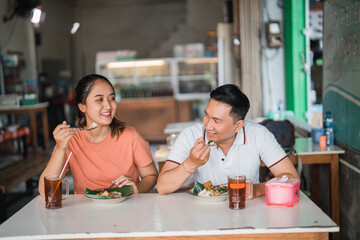 beautiful Asian woman and handsome man chatting over lunch at a table in a traditional food stall