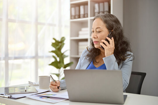 A Professional Mature Asian Female Boss Is On The Phone With A Supplier To Deal A New Contract