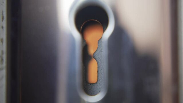 Unlock a door with key. Looking through keyhole perspective.