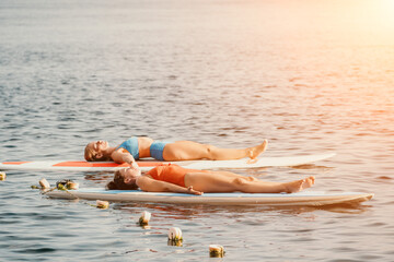 Woman sup yoga. Happy sporty woman practising yoga pilates on paddle sup surfboard. Female...