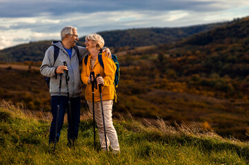 Obraz na płótnie Canvas Portrait of active senior couple with backpacks hiking together in nature on autumn day.