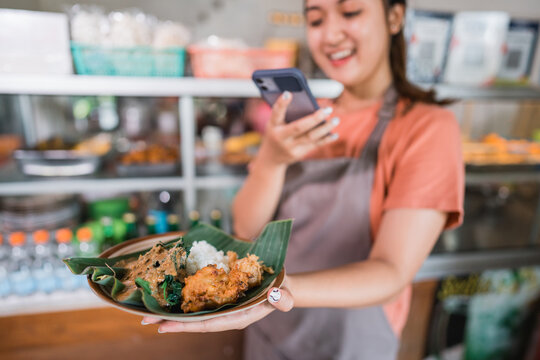a plate of pecel rice photographed using a cell phone camera by an Asian girl at a food stall