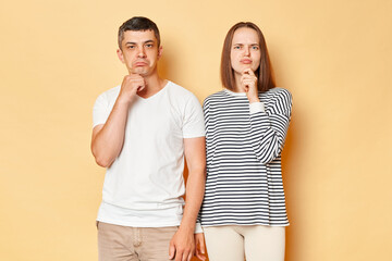 Pensivethoughtful young couple friends man woman in casual clothing isolated over beige background...