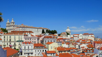 schöner  Aussichtspunkt  "Miradouro de Santa Luzia" in Lissabon mit weißen Häusern, roten Dächern, Kirchen, Meer und Sonne