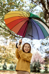 Portrait of caucasian girl in the park holding a colorful umbrella