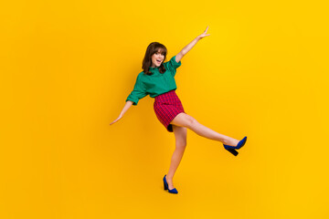 Full length photo of excited funky woman dressed green shirt walking having fun empty space isolated yellow color background