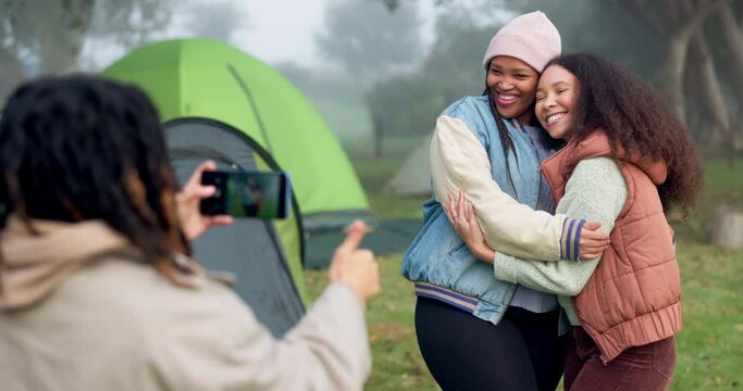 Women friends, photographer and smartphone at camping for hug, care or memory with smile, post or social network. People, profile picture and happy with phone, adventure or holiday in forest together