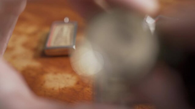 Using loupe to see the detail on an old Thai Buddha amulet