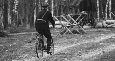 Re-enactor Dressed As Nkvd Forces Rides A Bike. Peoples Commissariat For Internal Affairs, Abbreviated Nkvd, Was Interior Ministry Of The Soviet Union. Black And White .