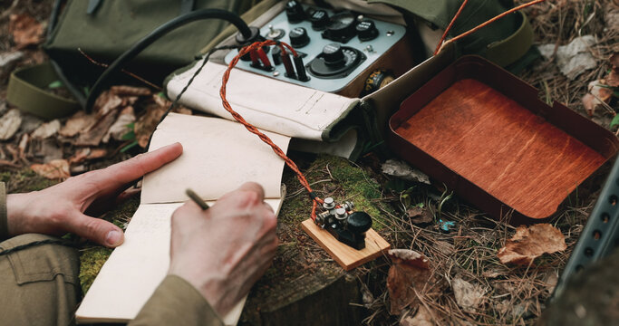Russian Soviet Infantry Red Army Soldier In World War II using Russian Soviet Portable Radio Transceiver In Trench Entrenchment In Spring Autumn Forest. . Headphones And Telegraph Key. Close Up Hands,