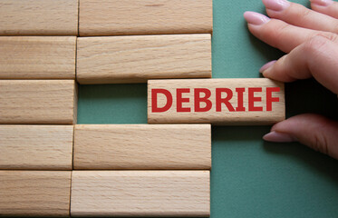 Debrief symbol. Concept word Debrief on wooden blocks. Businessman hand. Beautiful grey green...