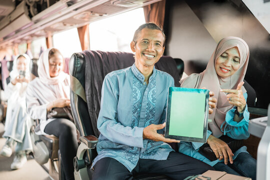 mature muslim couple using showing blank tablet screen to camera while riding a bus - Powered by Adobe