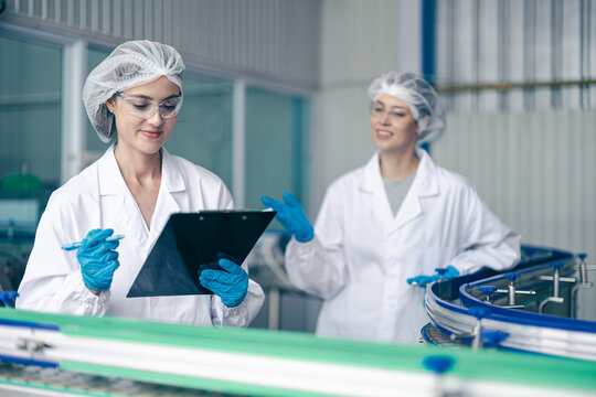 products control quality check team in conveyor belt production line in food and drink factory with hygiene uniform