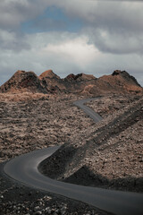 Carretera rodeada de roca volcánica con el volcán de fondo