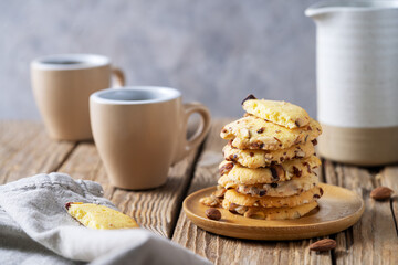 Florence cookies or fiorentine biscuits with almonds on wooden table with cups of coffee and cream jug