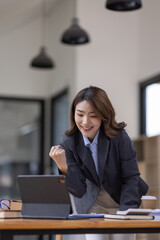 Excited asian woman sit at desk feel euphoric win online lottery, happy asian woman overjoyed get mail at tablet being promoted at work, biracial girl amazed read good news at computer
